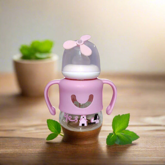 Pink baby bottle with a propeller on a white surface