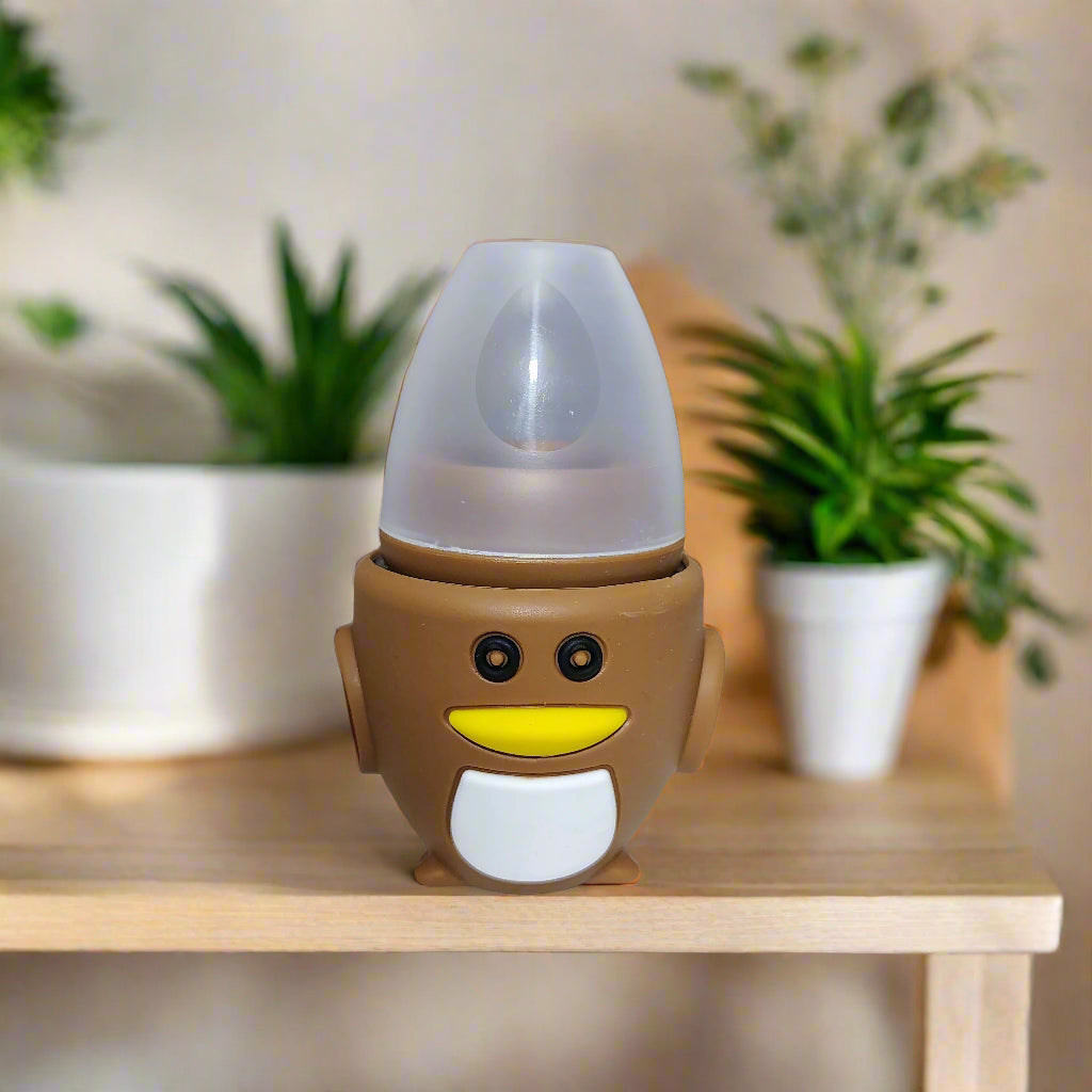 Penguin-shaped baby bottle on a white surface with a blurred indoor background