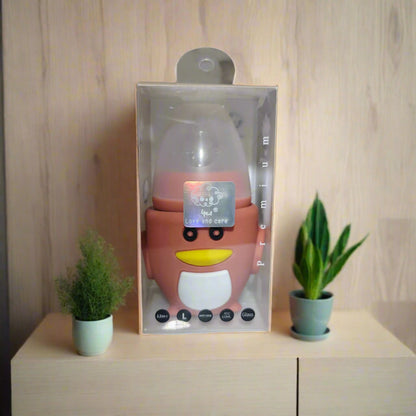 Pink cartoon-like bottle in packaging on a white surface with a blurred background