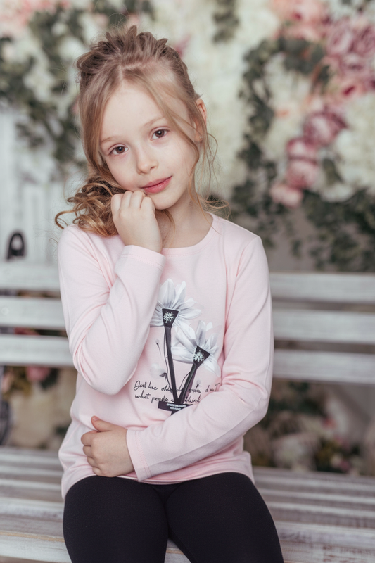 Young girl in a pink sweatshirt with a floral background